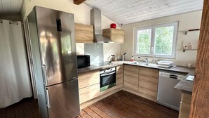 A modern kitchen with stainless steel appliances, wooden cabinets, and a window providing natural light. - Domaine du Dauphin (Cuers)
