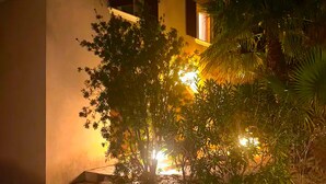 A building with a tiled roof and a well-lit entrance surrounded by vegetation. - Domaine du Dauphin (Cuers)