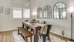 A dining area with a long wooden table, benches, and chairs, with three arched mirrors on the wall. - Las Vegas Home w/ Covered Patio ~ 5 Mi to Strip! (Las Vegas)