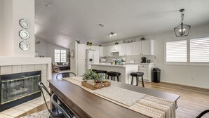 A modern kitchen with white cabinets, a wooden dining table, and a fireplace. - Las Vegas Home w/ Covered Patio ~ 5 Mi to Strip! (Las Vegas)