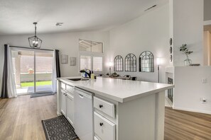 A modern kitchen with a large island, white cabinetry, and a view to the outside.