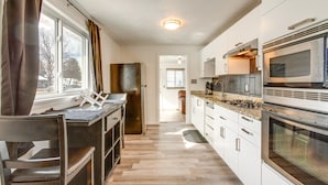A modern kitchen with a central island, stainless steel appliances, and a view through the window. - Covered Patio, Gas Grill & Yard: Sheridan Home! (Sheridan)