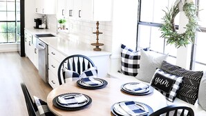 A modern kitchen with white cabinets, a dining table set for four, and a sign that reads "Say Grace". - New Year’s Retreat. Cozy Modern Farmhouse! Close to historic downtown Wylie! (Wylie)