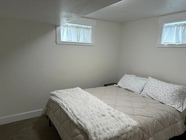 A bedroom with a bed, two windows, and a ceiling fan.