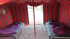 A tent with two beds, each with a striped blanket and pillows.