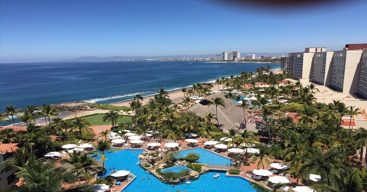 A resort with a pool, palm trees, and a beach view.