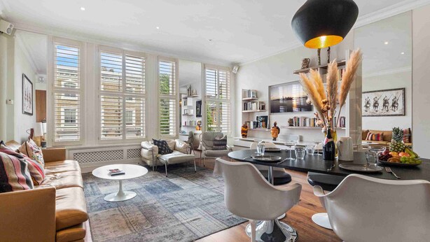 A modern living room with a sofa, coffee table, and dining area. - Chic Chelsea maisonette with 2 terraces (London)