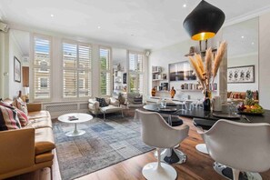 A spacious living room with a sofa, a coffee table, and a dining area with chairs and a table.