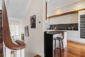 A modern kitchen with white cabinets, a black countertop, and a wooden floor.