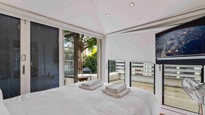 A modern bedroom with a large bed, sliding glass doors leading to an outdoor area, and a view of the city at night. - Chic Chelsea maisonette with 2 terraces (London)
