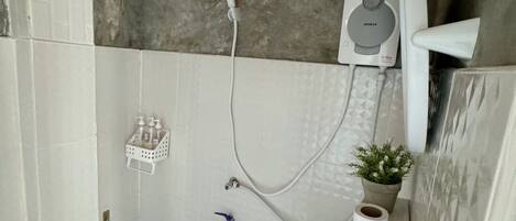 Ein Badezimmer mit einem weißen Waschbecken, einer Handbrause, einer Toilette und einem kleinen Topfpflanzen.