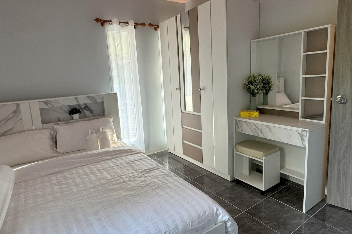 A bedroom with a bed, a wardrobe, a desk, and a mirror.
