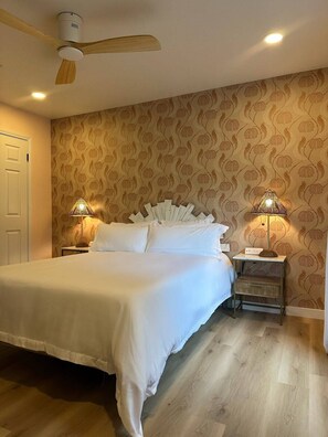A neatly made bed with white linens, a ceiling fan, and two bedside lamps. - Beautiful yard, cowboy pool, walk river trail/SoCo (Austin)