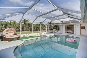A covered swimming pool with a built-in seating area and a floating ring. - Port St Lucie Canal-front Home w/ Heated Pool! (Port Saint Lucie)