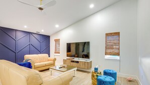 A modern living room with a sofa, coffee table, ottomans, and a TV. - Port St Lucie Canal-front Home w/ Heated Pool! (Port Saint Lucie)