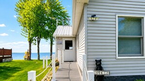 A house with a pathway leading to the entrance, a bear statue, and a view of the water.