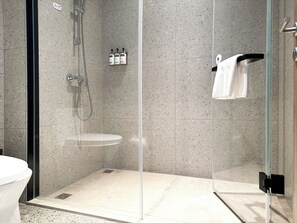 A modern bathroom with a glass-enclosed shower, a white sink, and a towel rack.