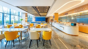 A modern hotel lobby with a breakfast bar, seating area, and large windows. - Holiday Inn Express Beijing Conference Center by IHG (Beijing)