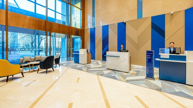 A modern hotel lobby with a reception desk, seating area, and large windows. - Holiday Inn Express Beijing Conference Center by IHG (Beijing)