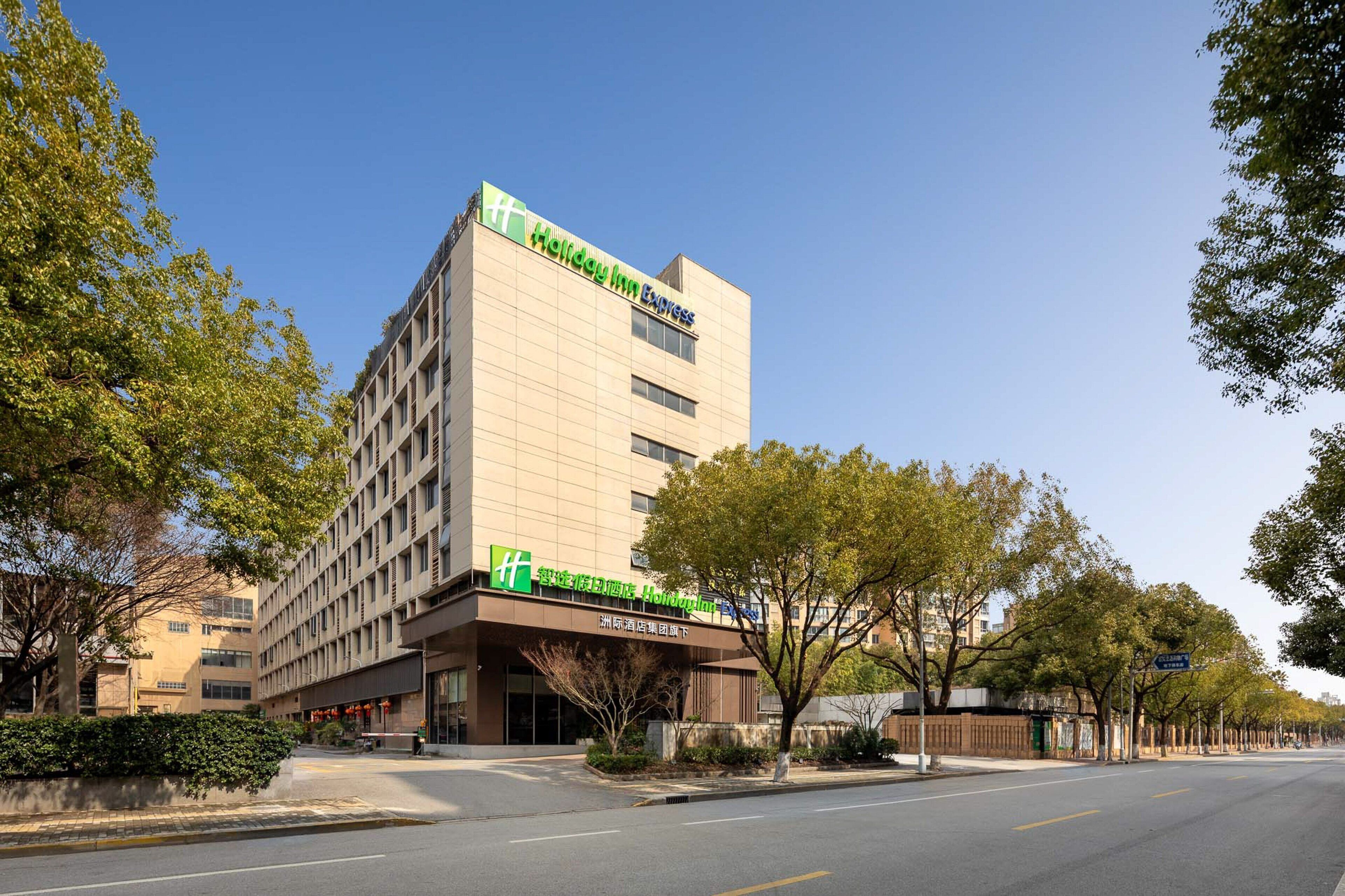 Un hotel Holiday Inn Express con un diseño moderno, situado en una calle arbolada.