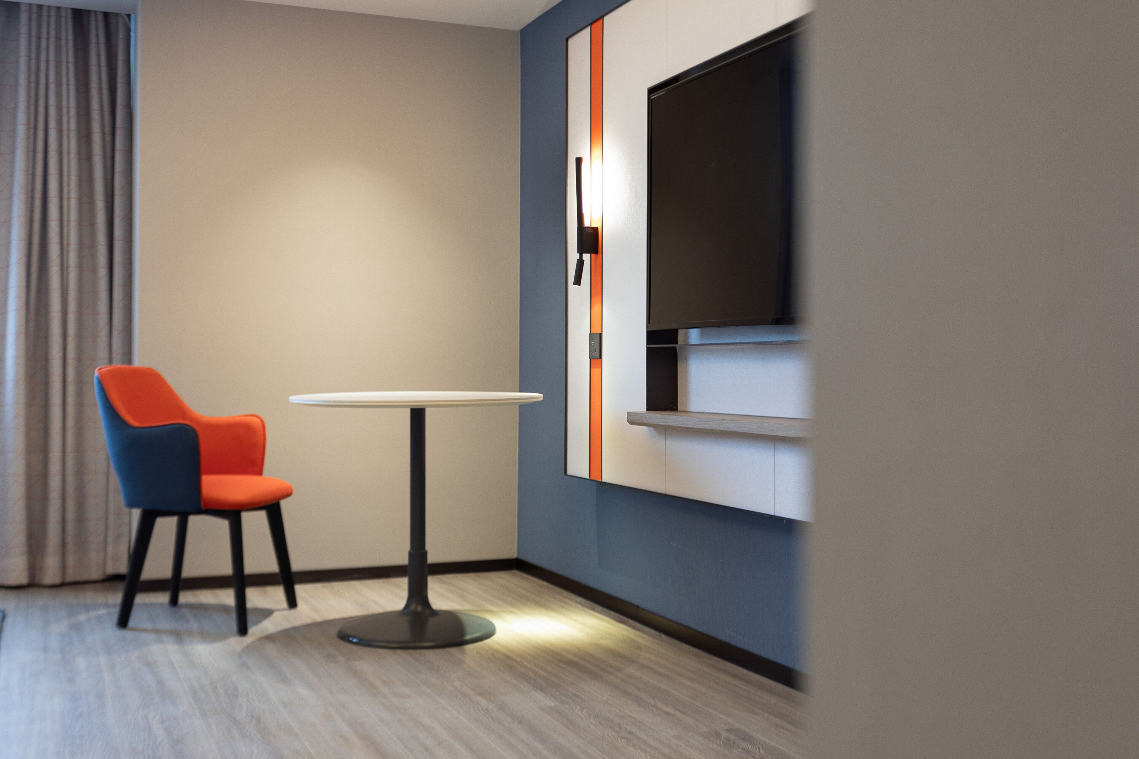 Una habitación moderna con una mesa redonda y una silla azul y naranja.
