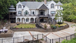 A large, multi-story house with a central staircase, a covered patio, and a fenced courtyard.