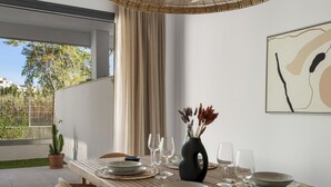 Een eettafel gedekt met borden, glazen en een vaas met gedroogde bloemen, in een kamer met een groot raam en een abstract kunstwerk aan de muur.
