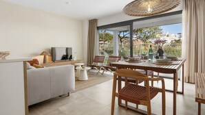 Een moderne woonkamer met een bank, televisie, eettafel en stoelen.