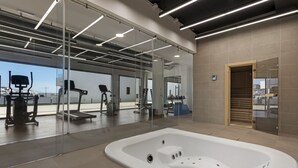 Een moderne sportschool met trainingsapparatuur, een grote glazen wand en een whirlpool.