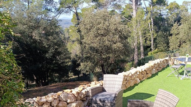 An outdoor seating area with wicker furniture and a stone wall. - Rez de Villa au Calme T2 + Terrasse Privative sur la Colline (Vidauban)