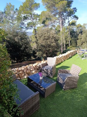 An outdoor seating area with wicker furniture and a stone wall. - Rez de Villa au Calme T2 + Terrasse Privative sur la Colline (Vidauban)