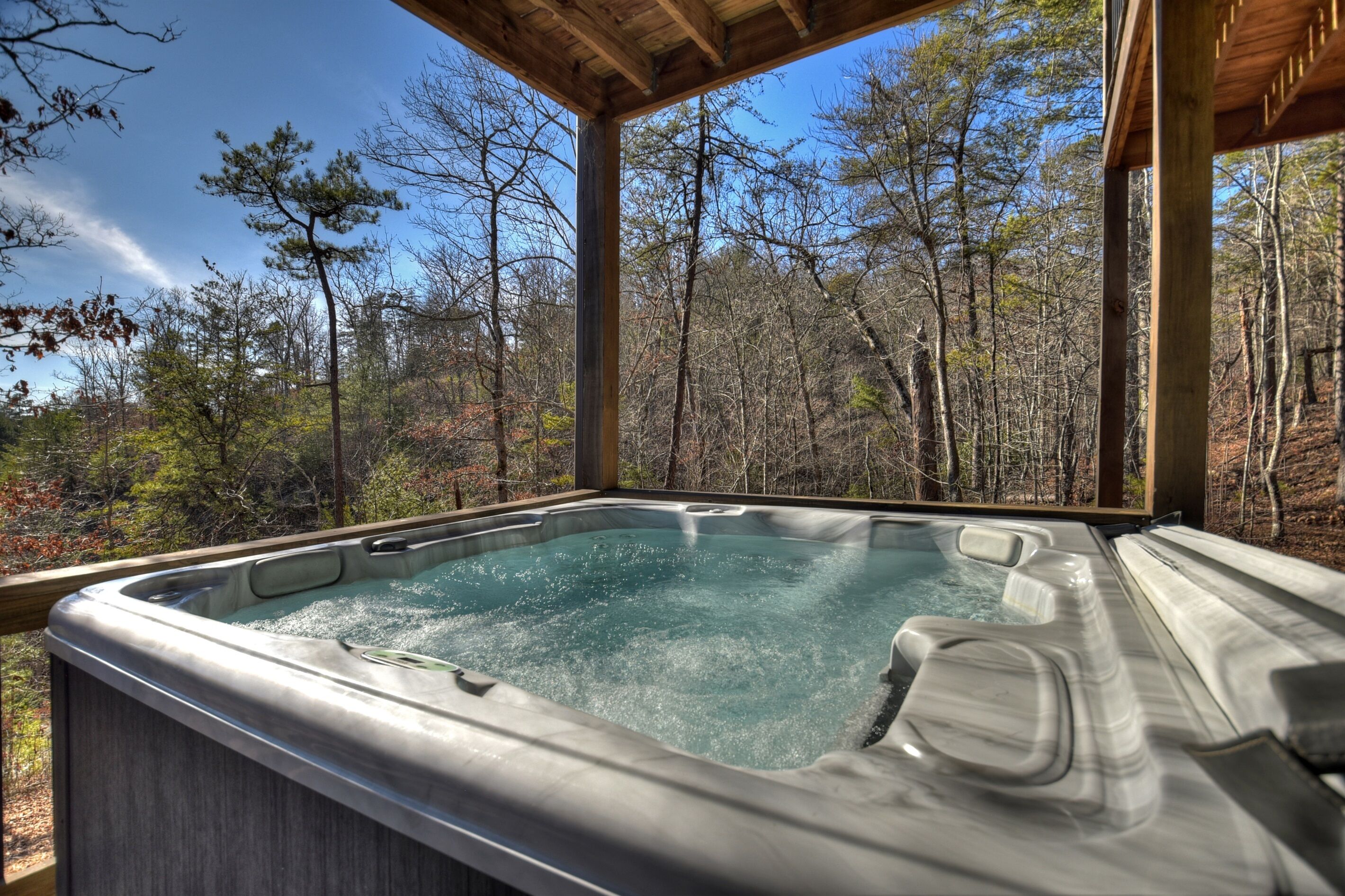 A hot tub in a wooden gazebo surrounded by trees.