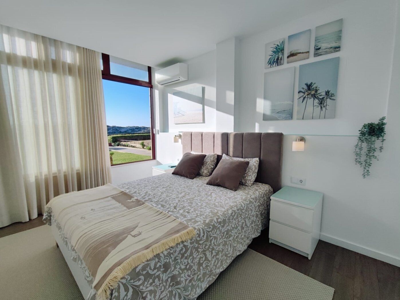Ein Schlafzimmer mit einem großen Bett, einem Nachttisch, einer Klimaanlage und Blick ins Freie.
