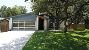Einbungalow mit Garage, Vorgarten und einem großen Baum.