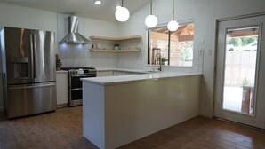 Eine moderne Küche mit einem Edelstahl-Kühlschrank, einem eingebauten Backofen und einer großen Kochinsel.