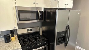 Una cocina compacta equipada con estufa a gas, horno, microondas y refrigerador.