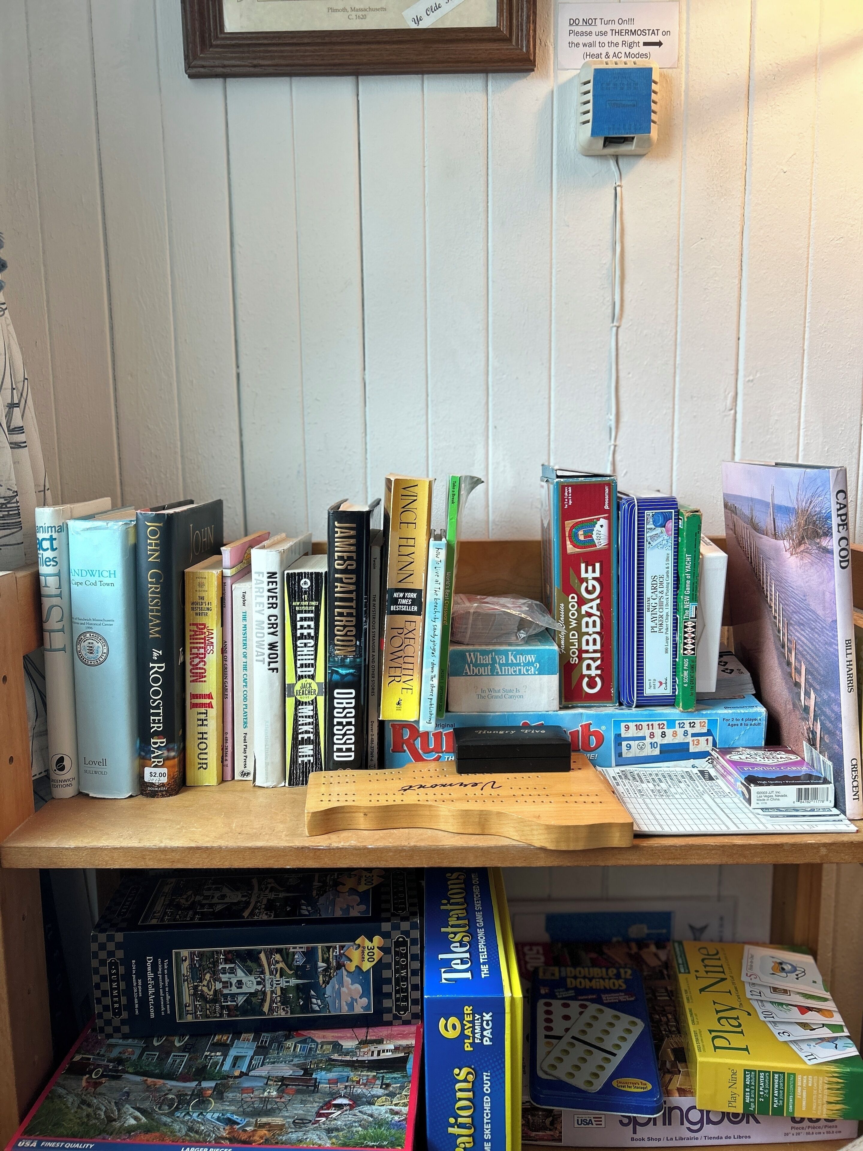 Una estantería con varios libros y juegos de mesa.