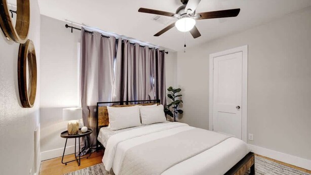 A bedroom with a bed, a ceiling fan, a door, and a small table with a plant. - Stylish Retreat Near Hot Springs Attractions (Hot Springs)