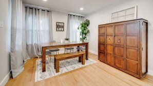 A dining area with a wooden table, bench, and chairs, a cabinet, and a potted plant. - Stylish Retreat Near Hot Springs Attractions (Hot Springs)