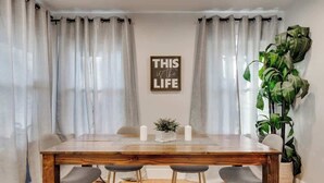 A dining area with a wooden table, four chairs, two candles, a small plant, and a wall-mounted sign. - Stylish Retreat Near Hot Springs Attractions (Hot Springs)