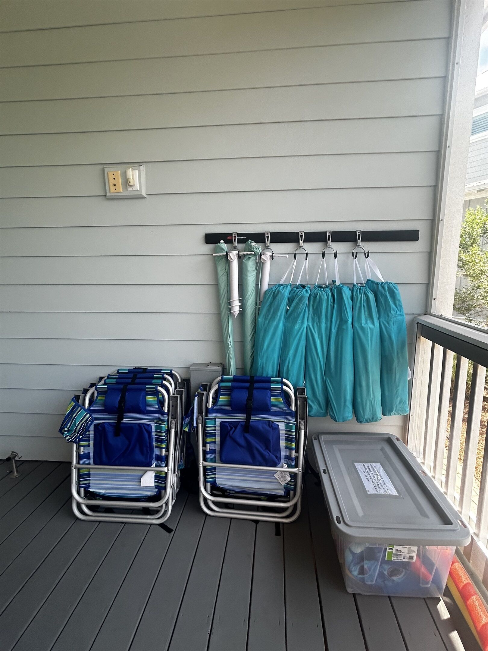 Un balcone con due carrelli portabagagli in metallo, un contenitore di plastica e uno stendibiancheria con capi di abbigliamento color acquamarina.