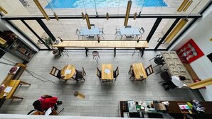 A rooftop bar with a pool view, wooden tables, and chairs. - Embassy Gardens Apartment (Accra)