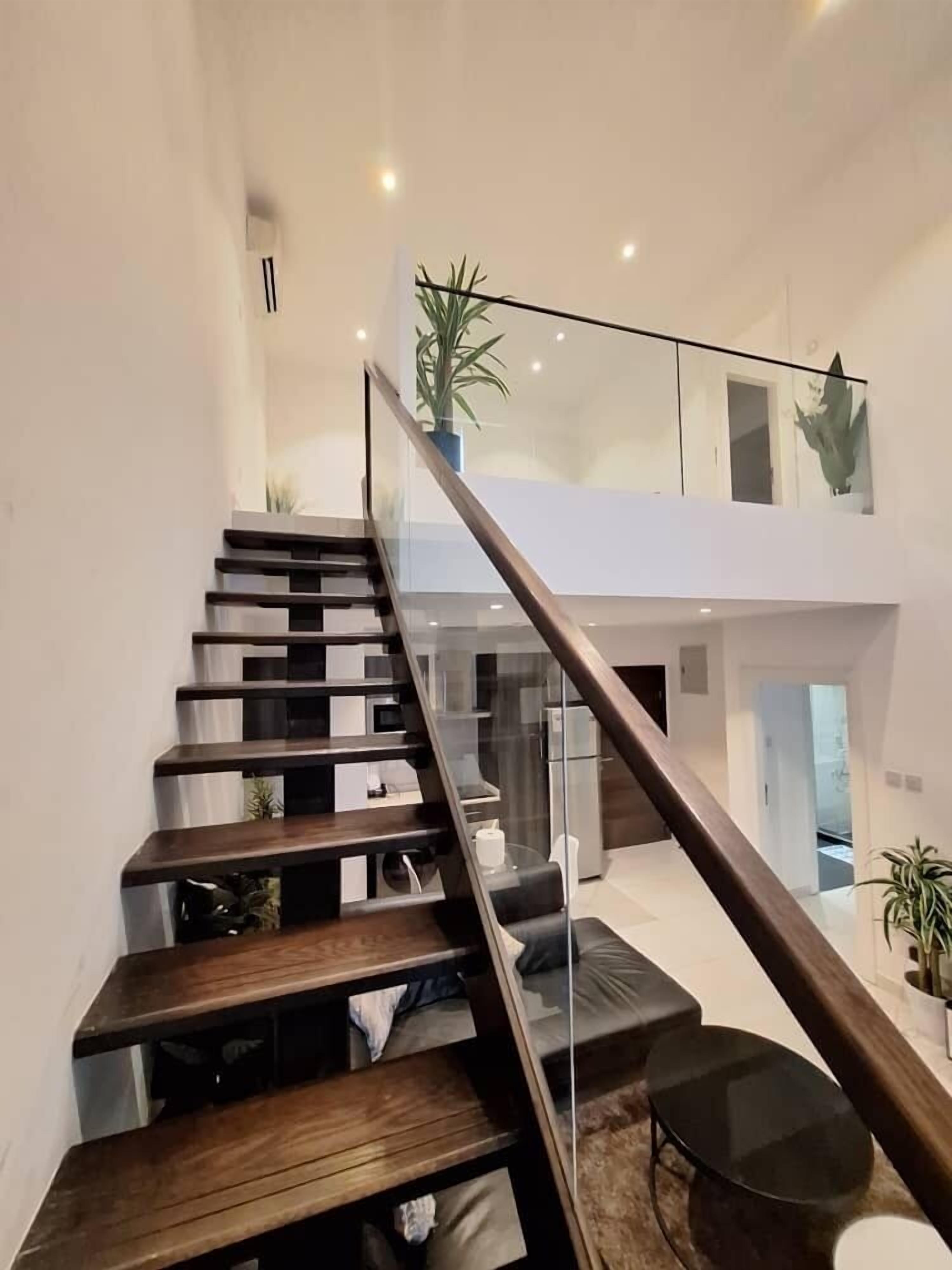 A modern staircase with glass railings leading to a second-floor living area.