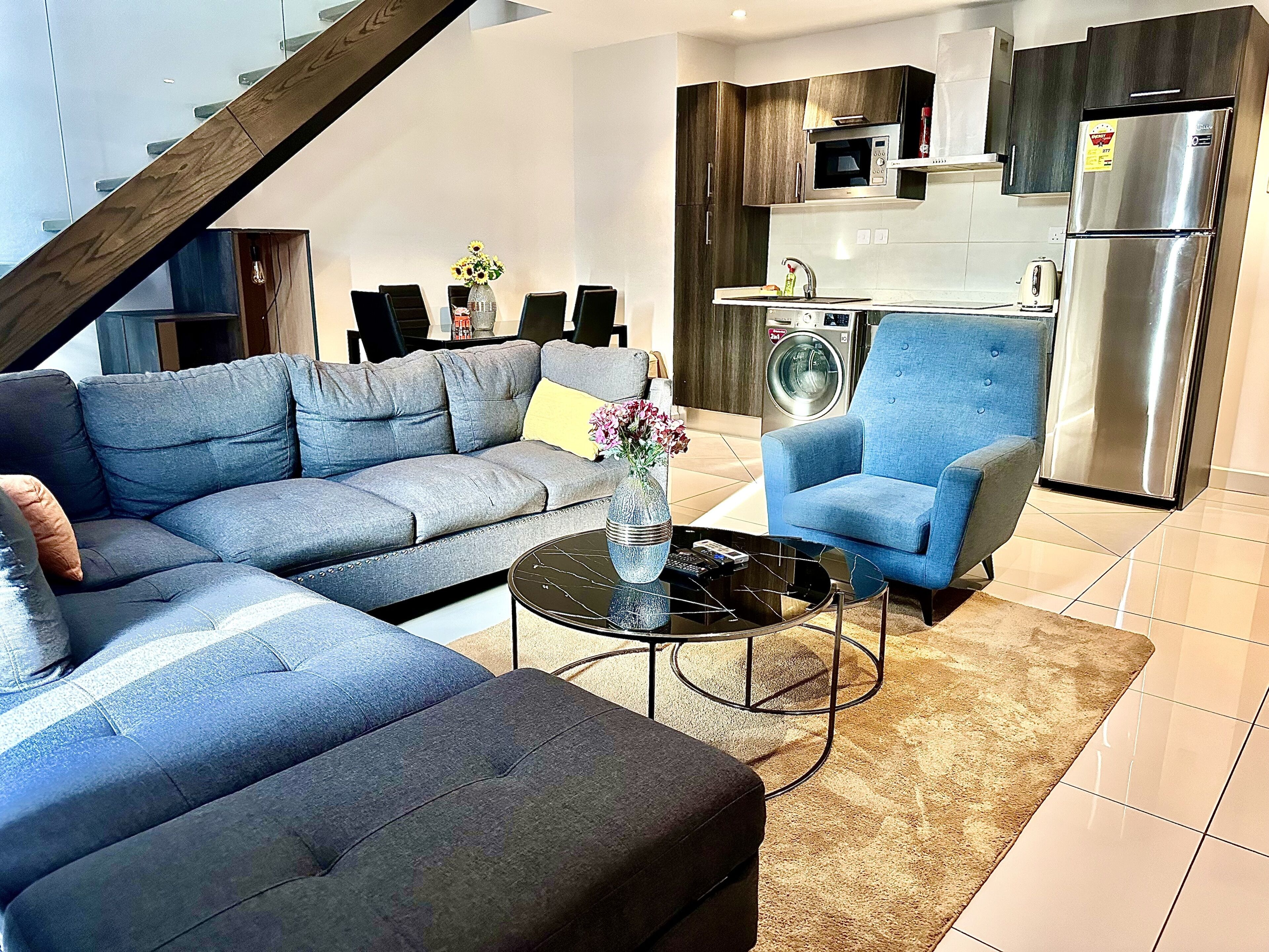 A modern living room with a grey sectional sofa, a blue armchair, and a coffee table.