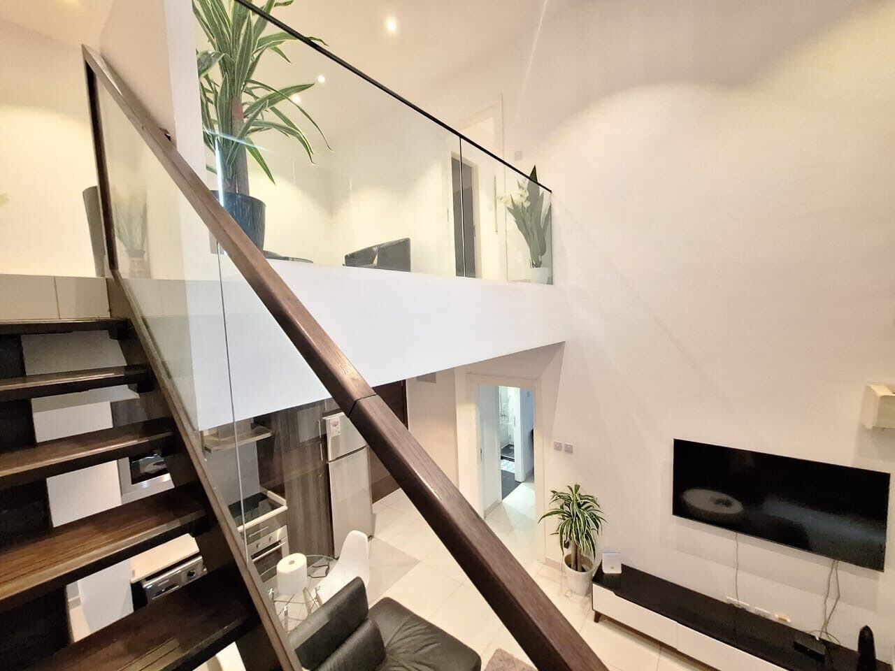 Ein modernes Interieur mit einer Treppe zu einer zweiten Etage, einem Essbereich und einem Wohnraum mit einem Flachbildfernseher.