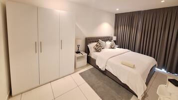 A modern bedroom with a large wardrobe, a bed with a headboard, and a nightstand.