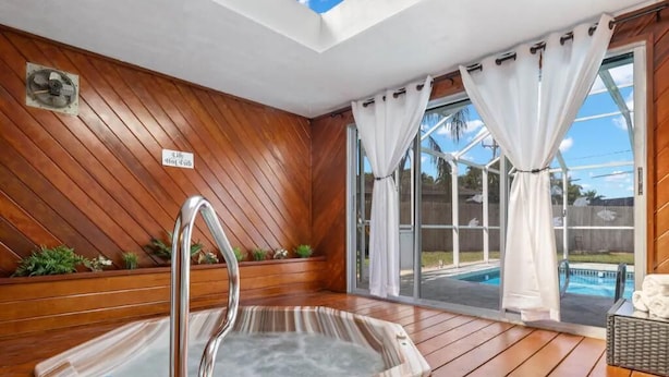A hot tub in a wooden deck area with a view of a backyard pool. - Hot tub, Gazebo, Firepit Table Getaway Oasis House!!!! (Fort Myers)