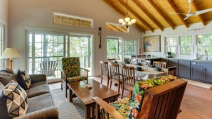A spacious living area with a high ceiling, wooden beams, a dining table, and a kitchen area with a sink and cabinets.