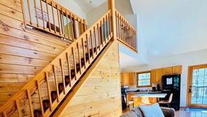 Un intérieur moderne avec un escalier en bois, un canapé en cuir et un coin cuisine.