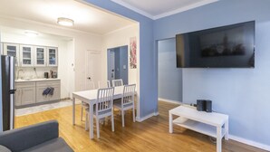 A modern living room with a dining area, a kitchen, and a TV mounted on the wall. - Amazing 2 BR on Upper East Side NYC (New York)